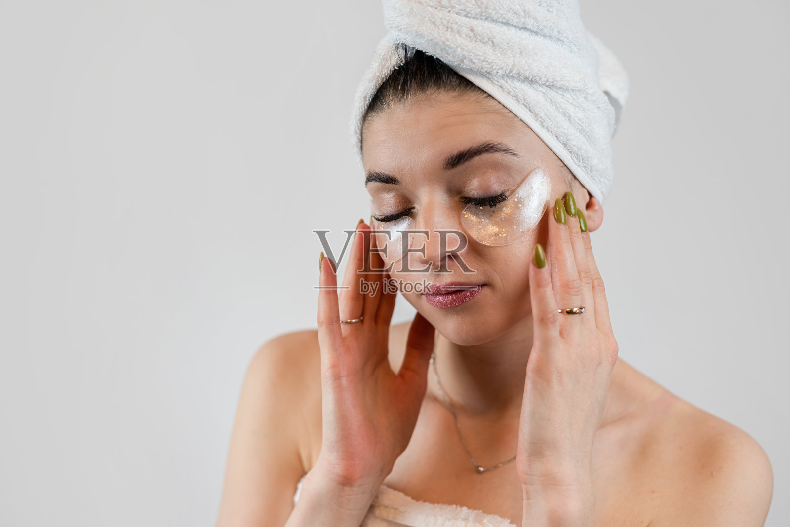 漂亮的年轻女子正在使用胶原蛋白贴片，以平滑眼睛下的皮肤，孤立于白色照片摄影图片