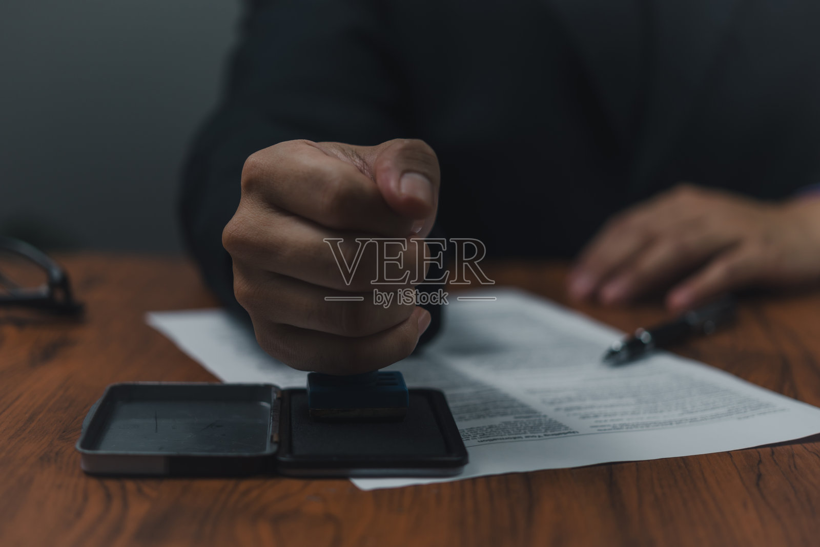 公证员在公证处盖章。商务人员在办公桌上盖章批准工作、金融、银行或投资营销文件。照片摄影图片