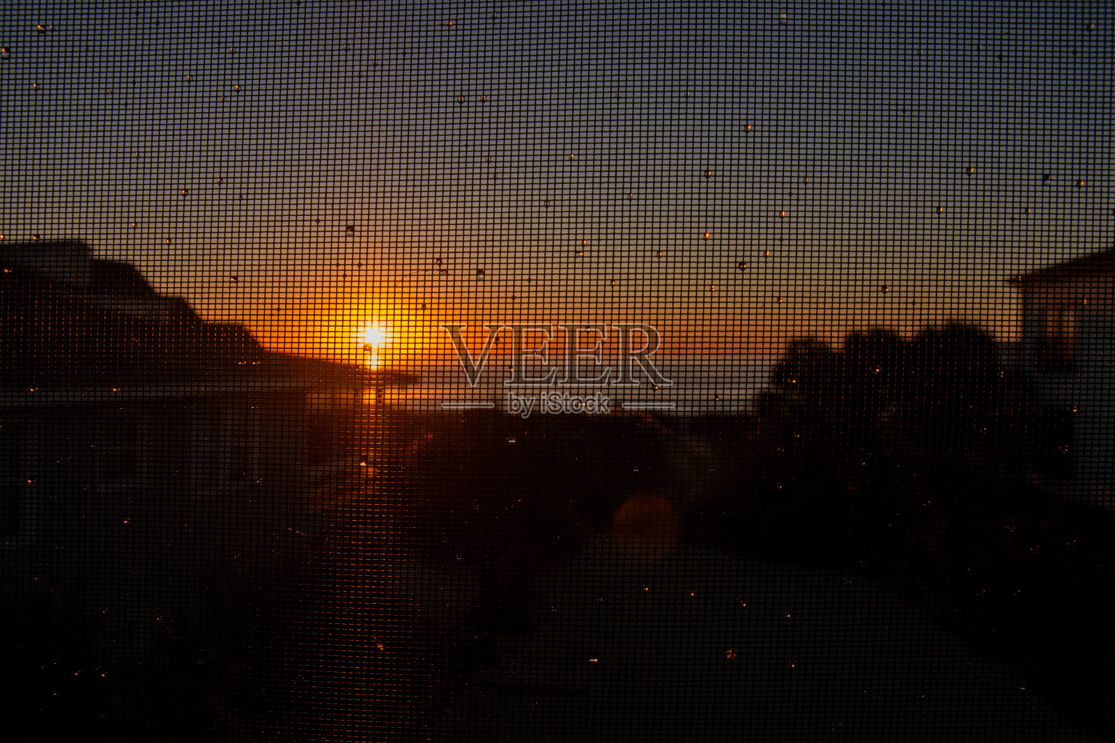 海滩上的日出透过门廊的纱窗照片摄影图片