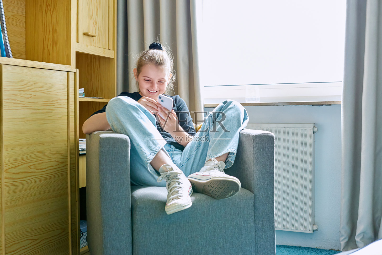 10、11岁的女孩拿着智能手机坐在椅子上照片摄影图片