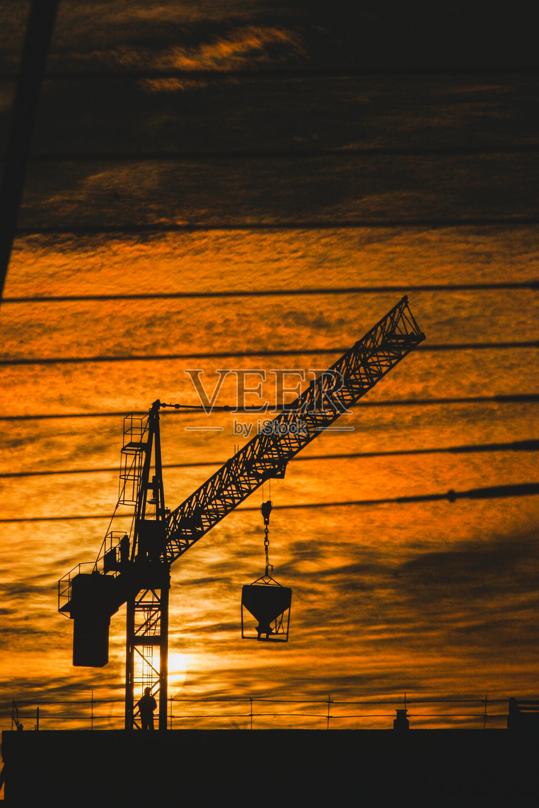 夕阳下，一名工人在工地上驾驶起重机照片摄影图片