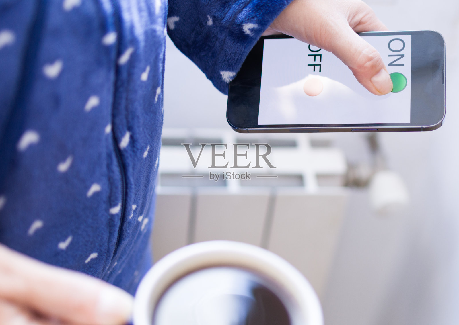 冬季，女人用手机开启家庭供暖，实现家庭自动化和APP远程控制温度照片摄影图片