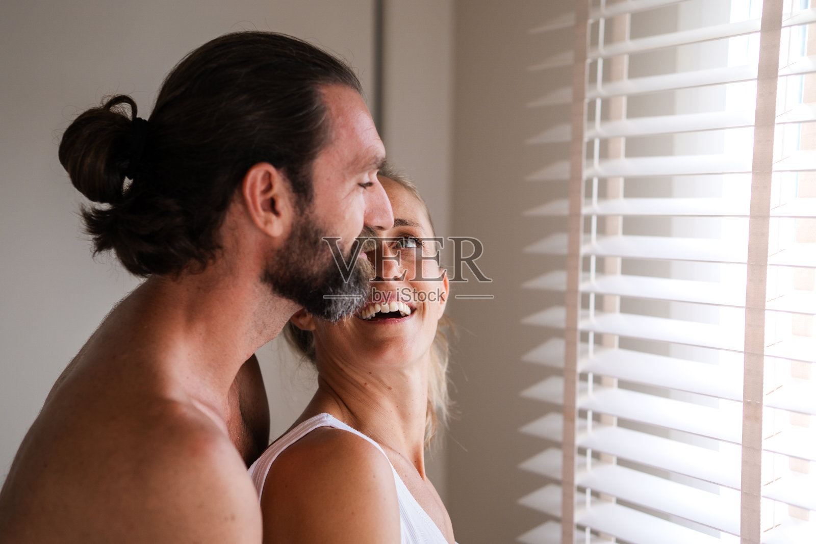 金发女人转身看着从背后拥抱她的丈夫照片摄影图片