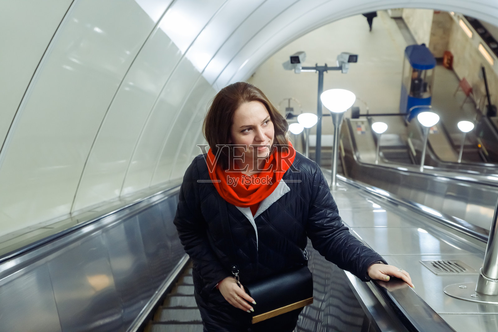 看向别处，微笑的中年高加索女性在地铁上自动扶梯。生活方式照片摄影图片