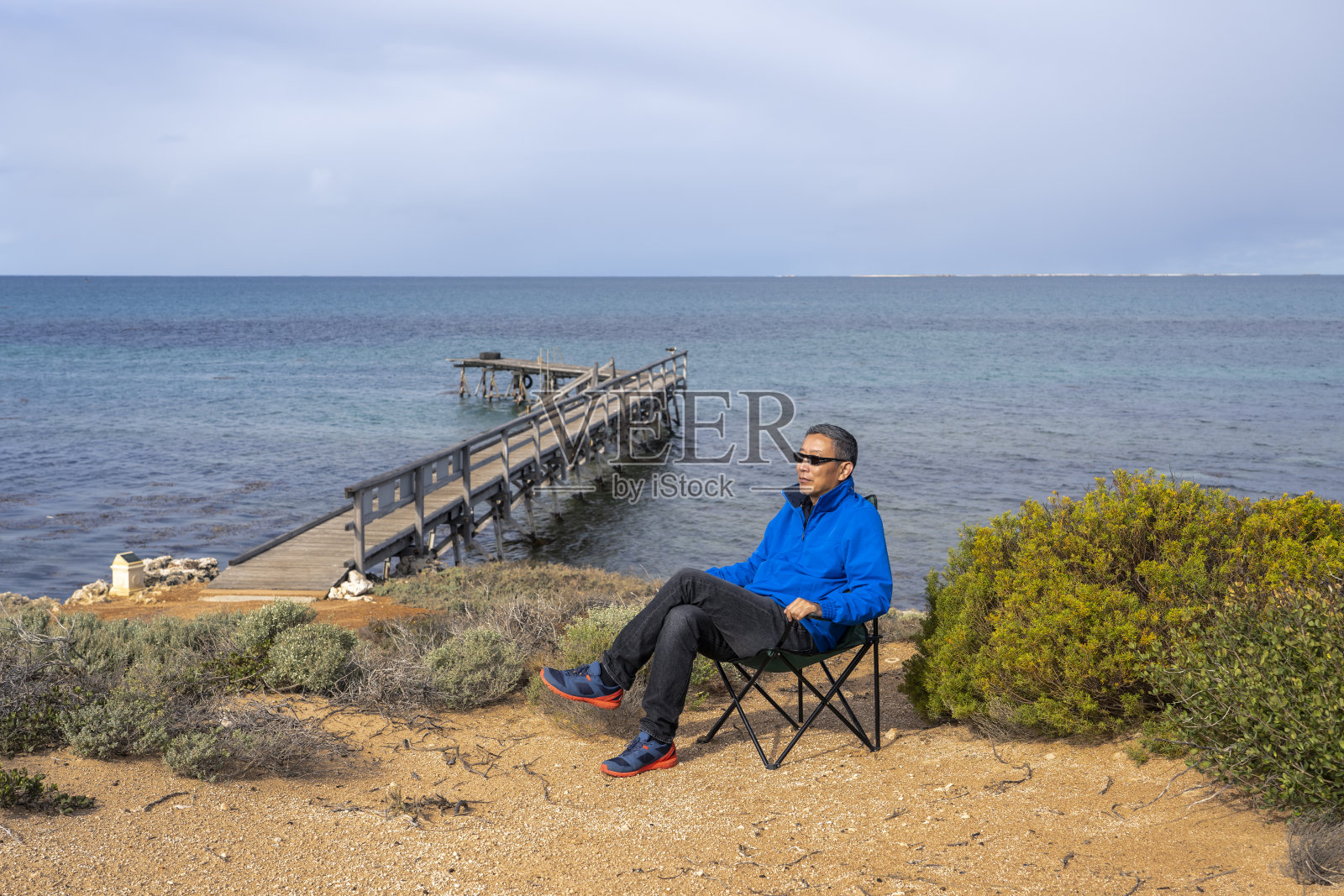 一个男人坐在海边晒太阳，西澳大利亚，澳大利亚照片摄影图片