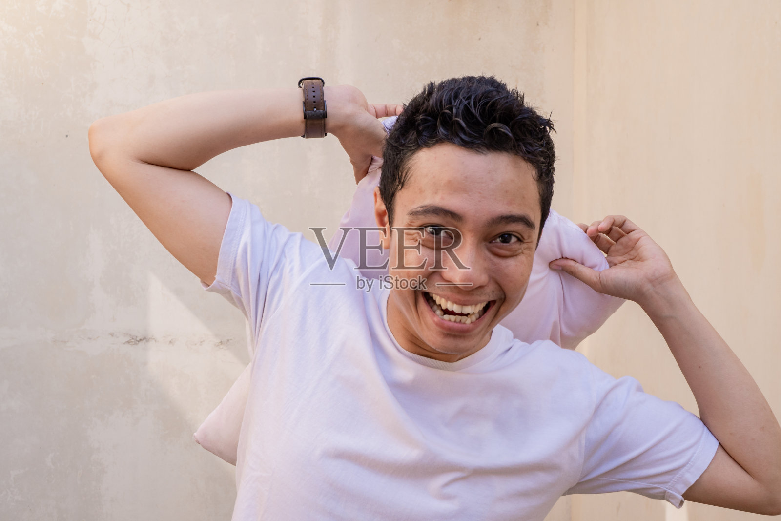 印度尼西亚男人和朋友打枕头时摆姿势，脸上带着快乐的表情。照片摄影图片