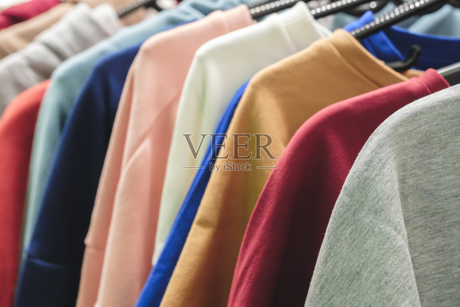 时尚帽衫衣服在衣架上的彩虹色选择的特写女性穿在衣架上在一个服装店的衣柜夏季家庭衣柜。照片摄影图片