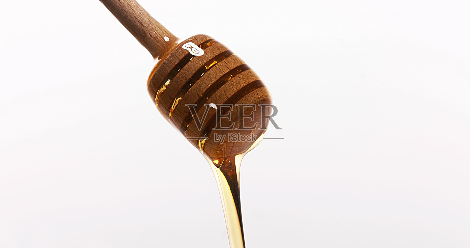 蜂蜜从勺子流出，背景是白色的照片摄影图片