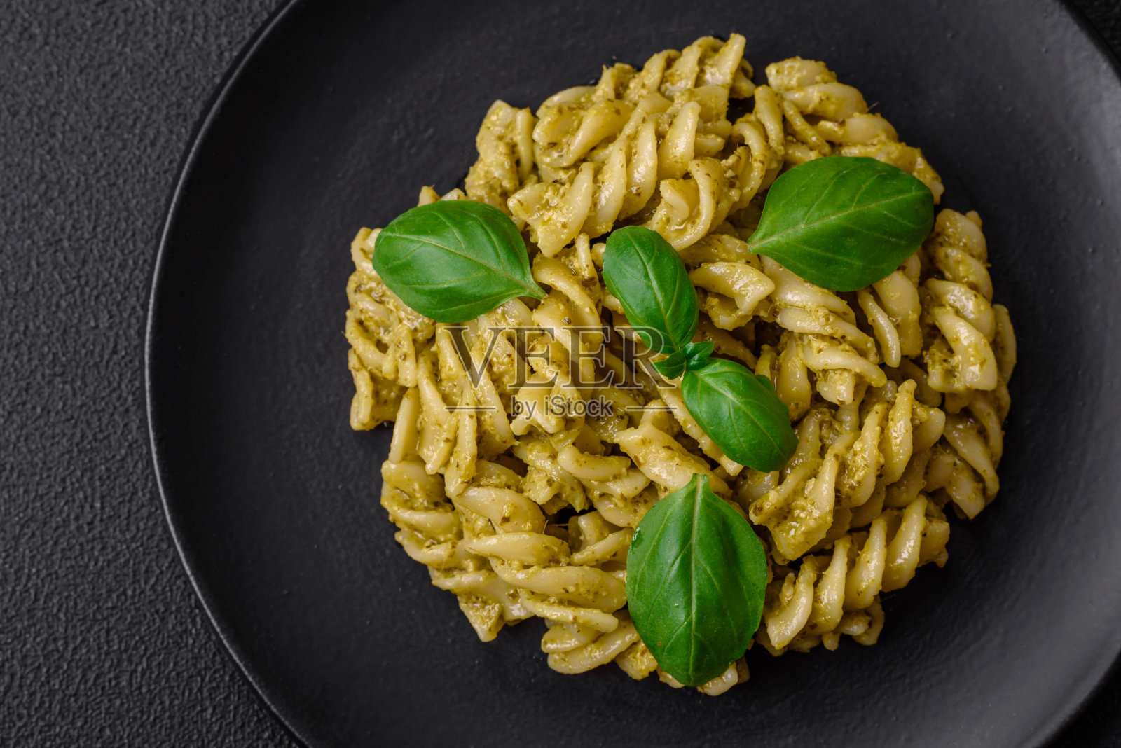 美味的新鲜意大利面配上绿色香蒜酱和罗勒照片摄影图片