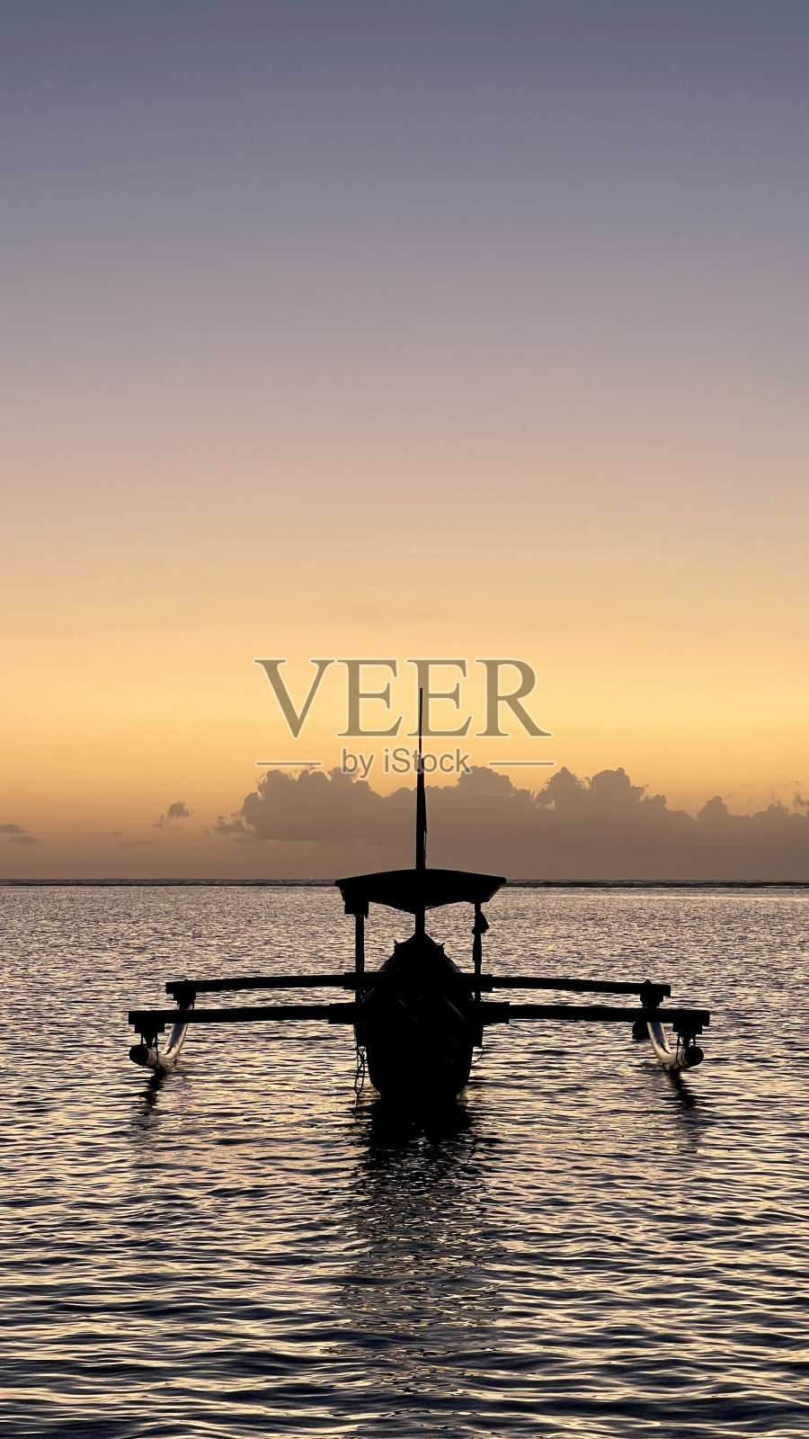 日出时在巴厘岛沙滩上的印尼渔船。照片摄影图片