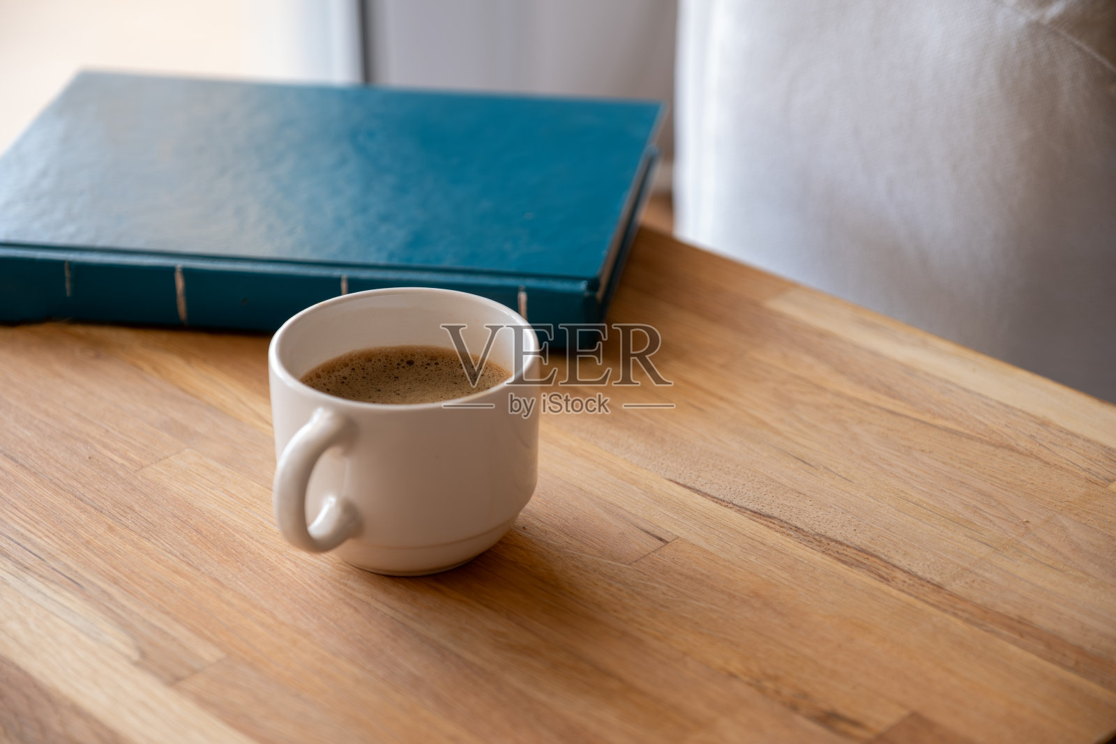 书本旁的木质背景上的白色咖啡杯照片摄影图片