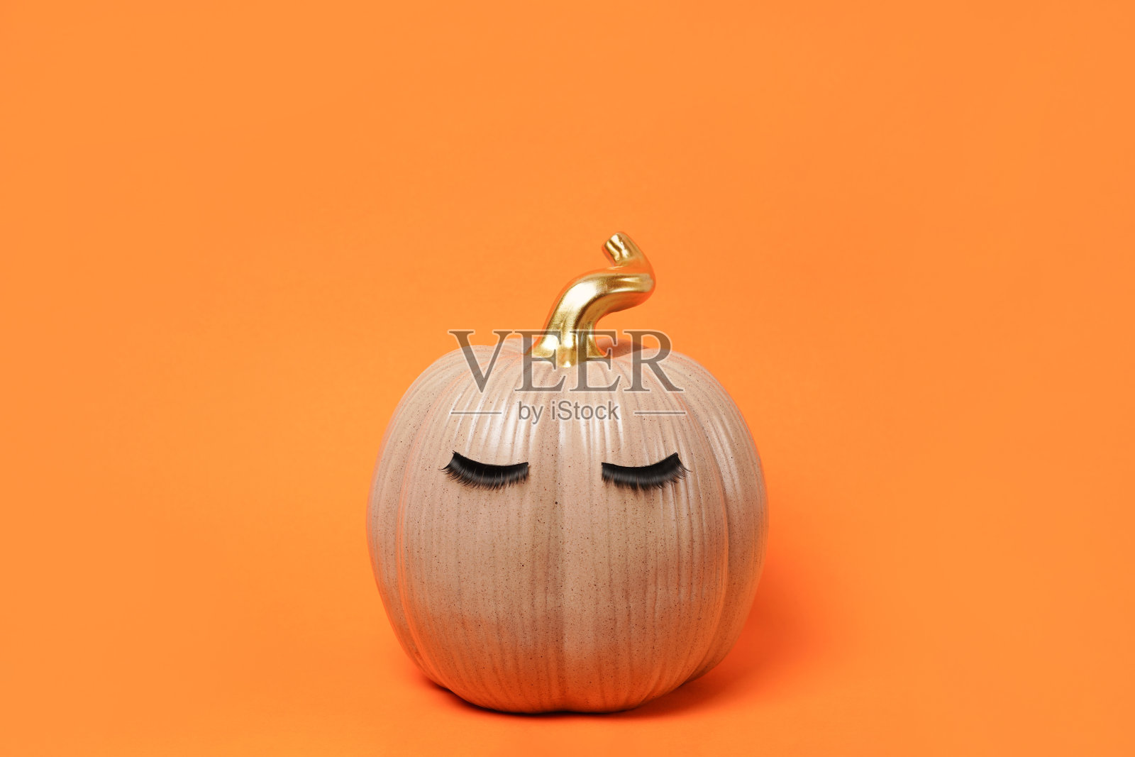 万圣节南瓜与假睫毛在明亮的橙色背景。秋天，秋天，美丽的概念。本空间照片摄影图片