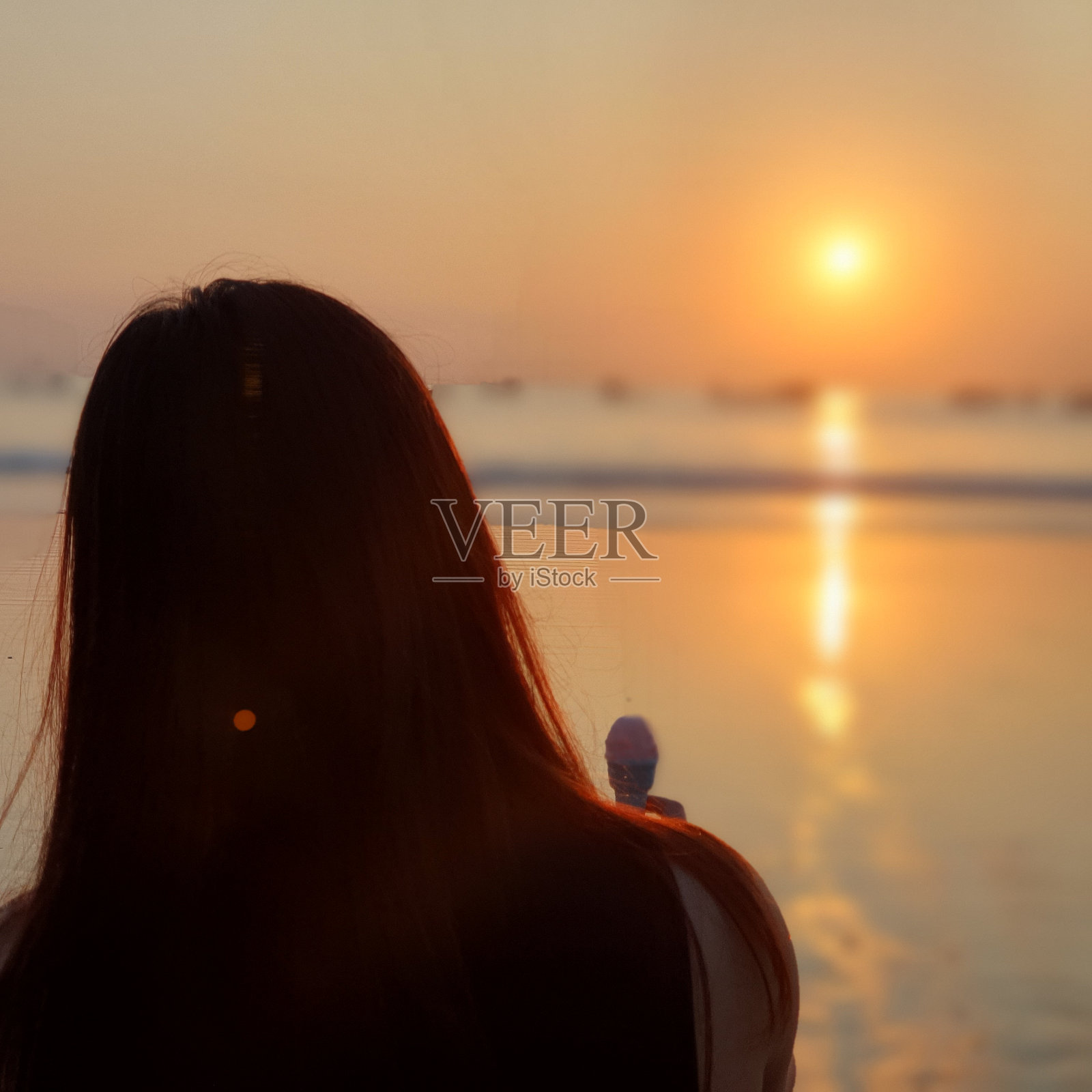 在夕阳下吃冰淇淋的女人照片摄影图片