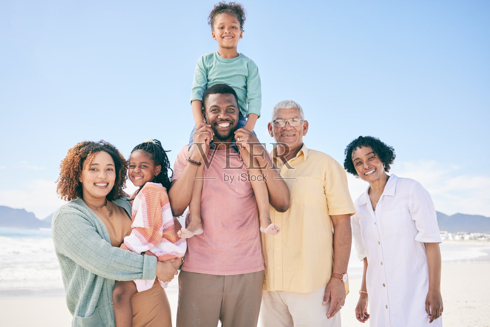 肖像，爱和家人在海滩上，质量的时间和幸福与欢乐，愉快和冒险。面对，快乐的爷爷奶奶和妈妈带着爸爸、兄弟姐妹和孩子们在海边度假和度假照片摄影图片
