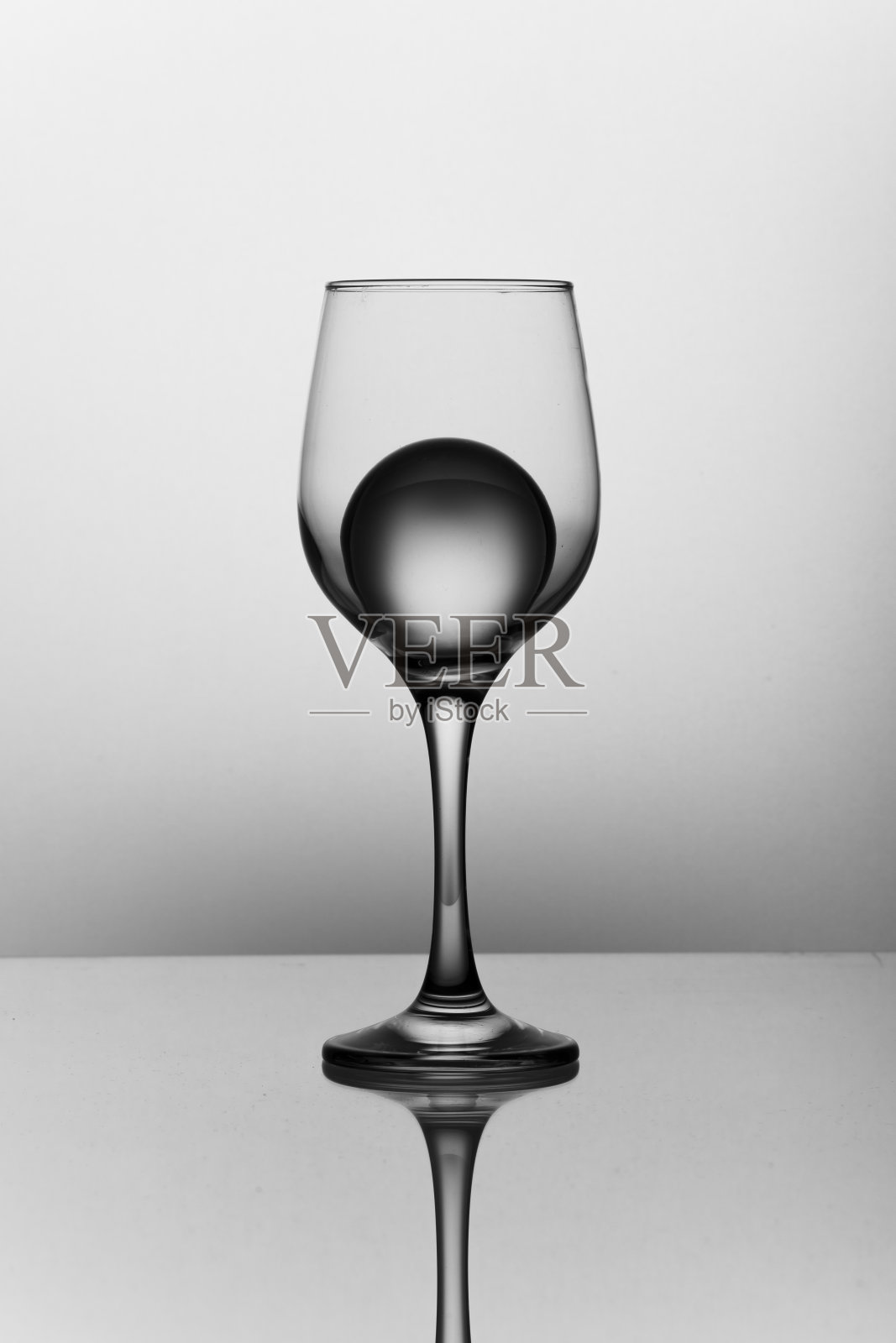 一个背光的葡萄酒杯被隔离在白色背景上，里面有一个冰球。照片摄影图片