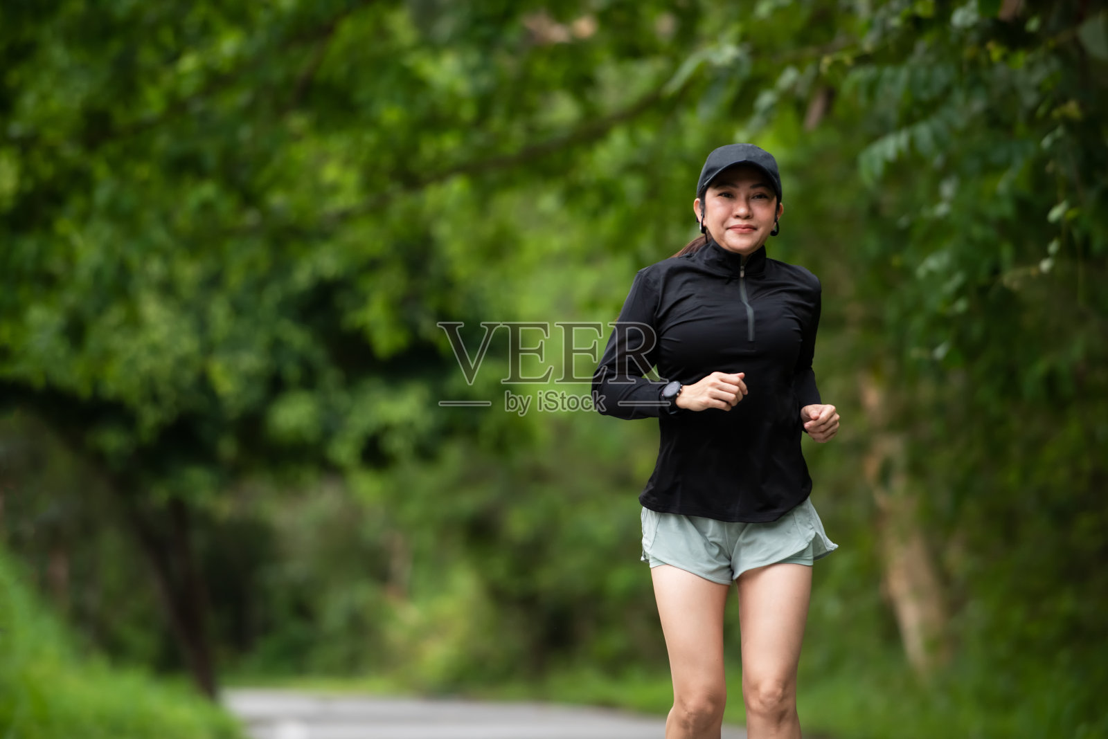 健康妇女慢跑跑步和户外道路锻炼。亚洲跑步者以健身为主，以自然公园为背景。健康生活理念照片摄影图片