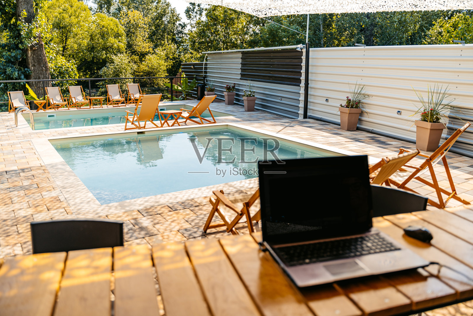 在后院游泳池的桌子上放着笔记本电脑照片摄影图片