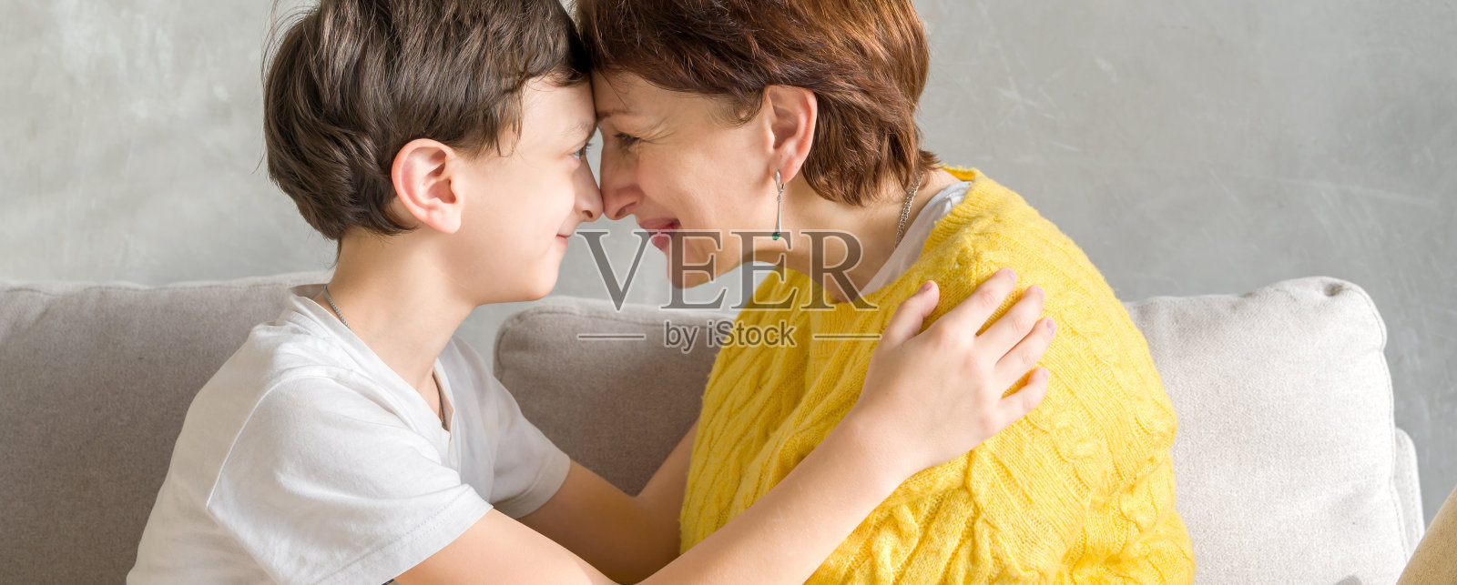 母亲和儿子碰着鼻子微笑着。幸福的家庭照片摄影图片