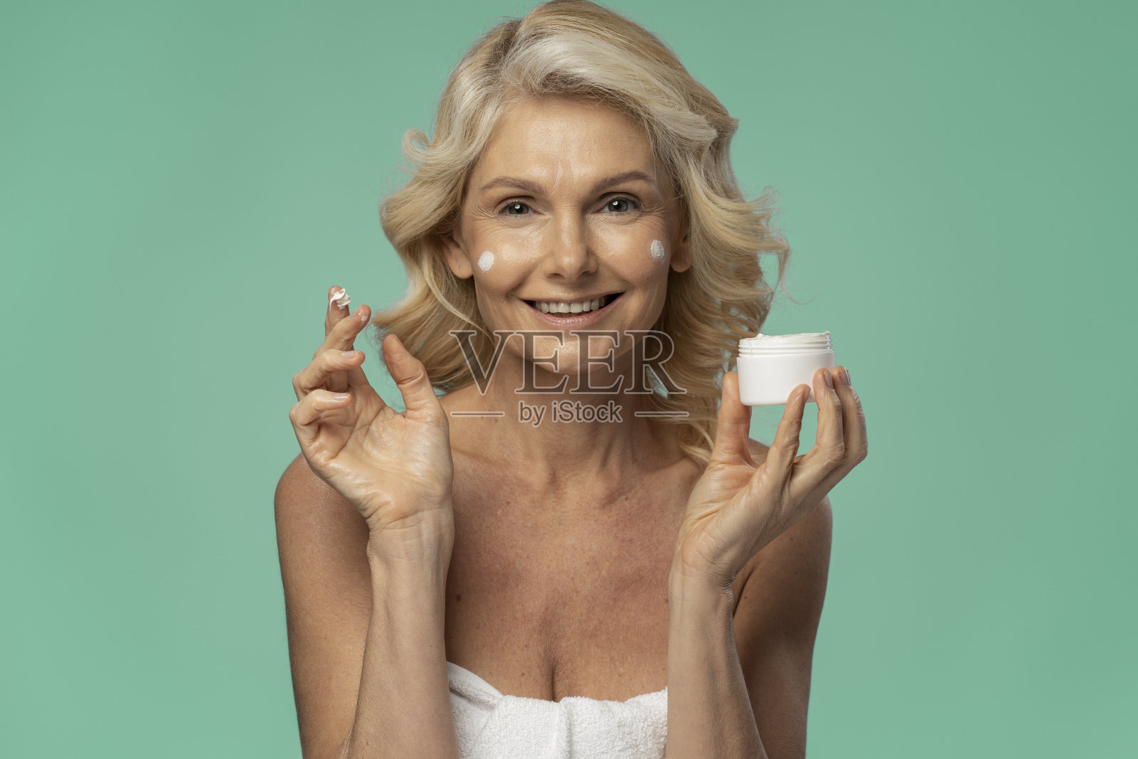 美丽的微笑自信的女人拿着罐子化妆霜隔离照片摄影图片