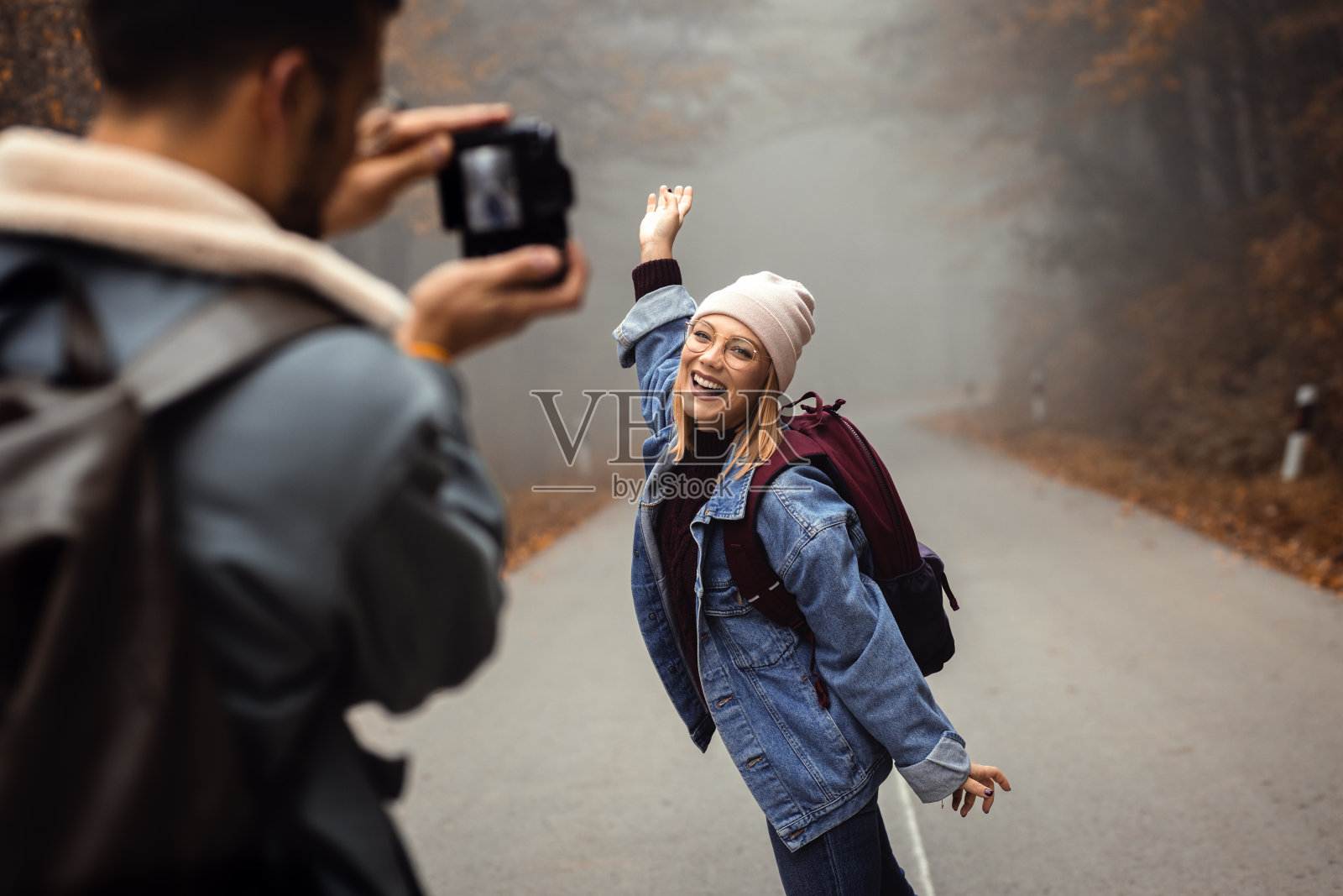 一对情侣在雾蒙蒙的早晨漫步在林间小路上，互相拍照。照片摄影图片