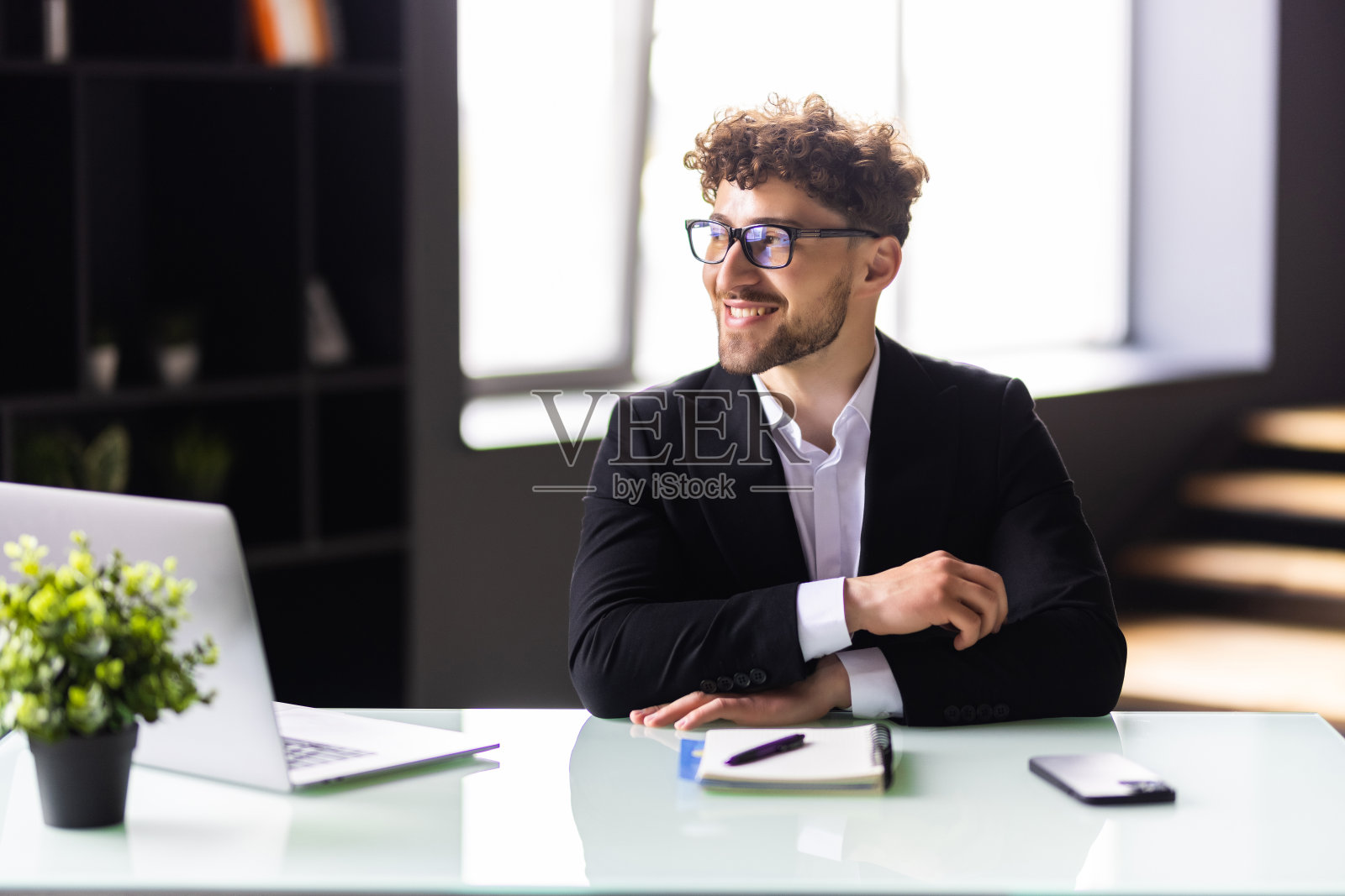 在开放式办公室里用笔记本电脑工作的富有创造力的商人。照片摄影图片