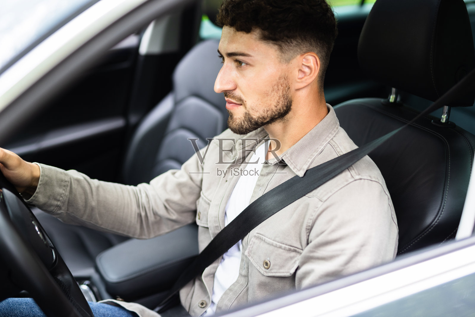 年轻的西班牙裔男子在街上开车系安全带照片摄影图片