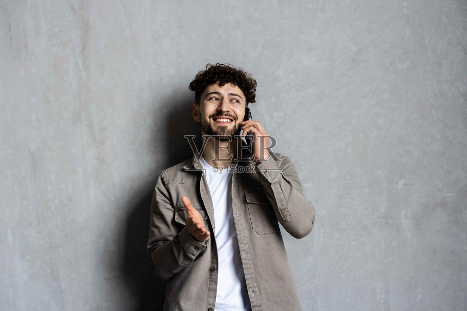 年轻人一边打电话一边微笑着工作照片摄影图片