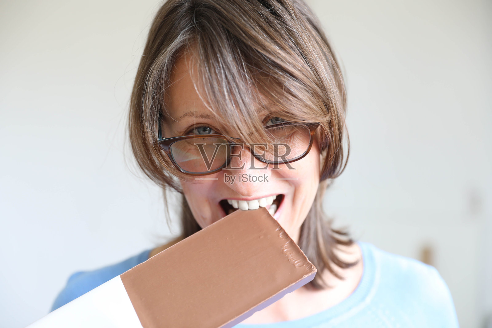 快乐的成熟女人吃巧克力。照片摄影图片