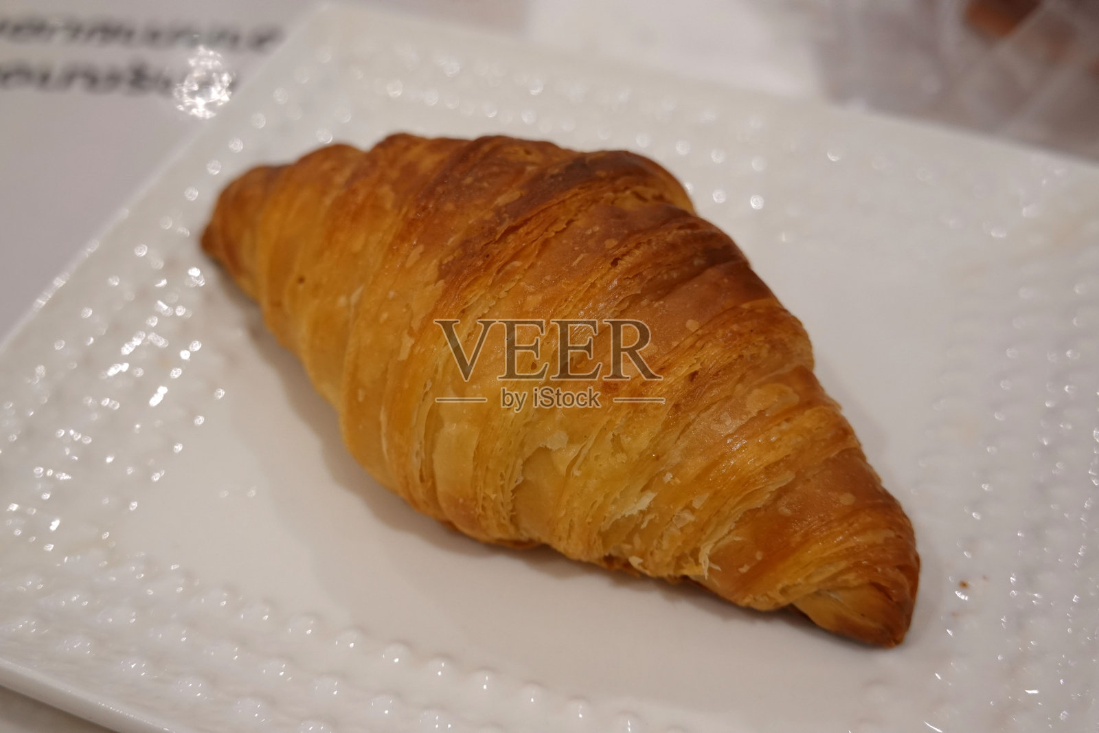 白盘子上刚烤好的羊角面包。法国早餐照片摄影图片