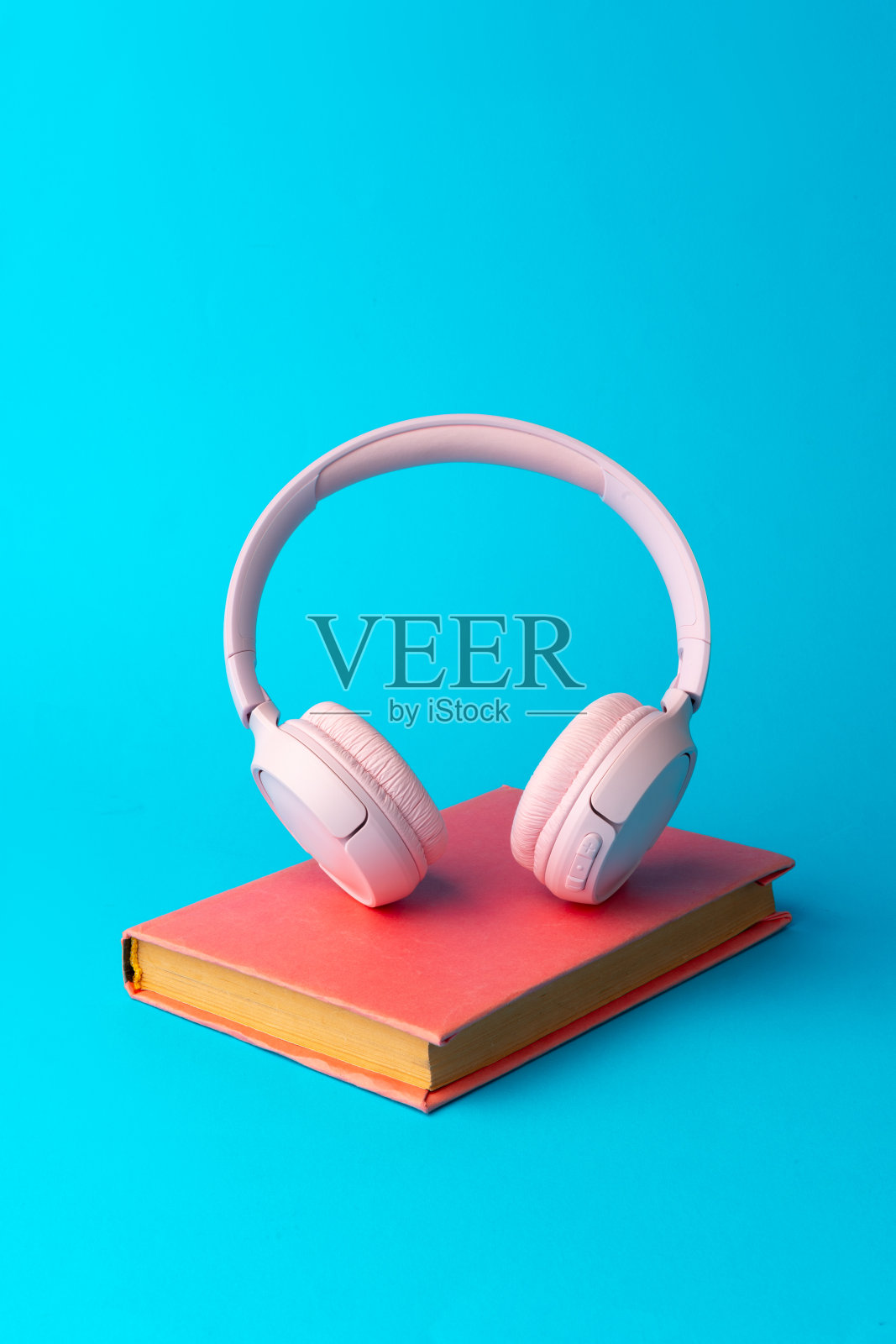粉色耳机配上蓝色背景的书照片摄影图片