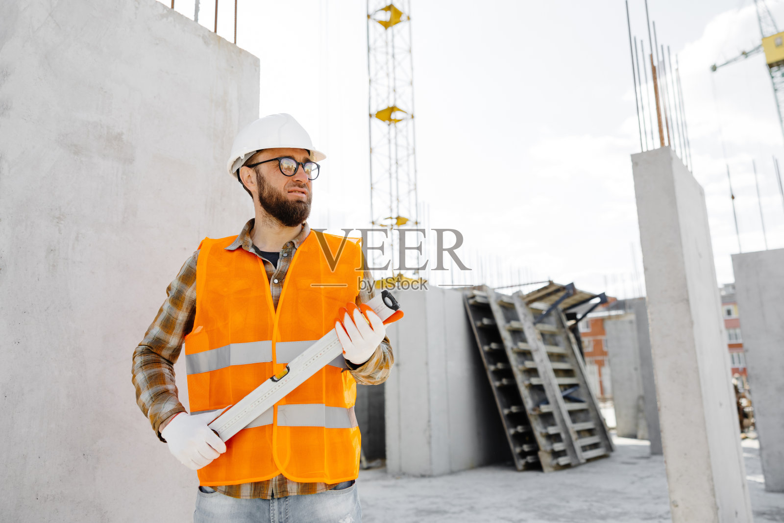 戴着防护头盔和背心的建筑工人、修理工、工头站在大楼的工作场所，手里拿着尺子照片摄影图片