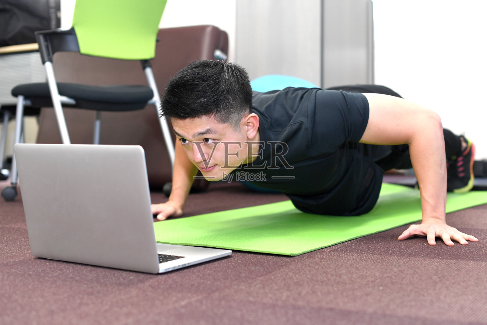 年轻的亚洲男子在电脑前做俯卧撑重量训练照片摄影图片