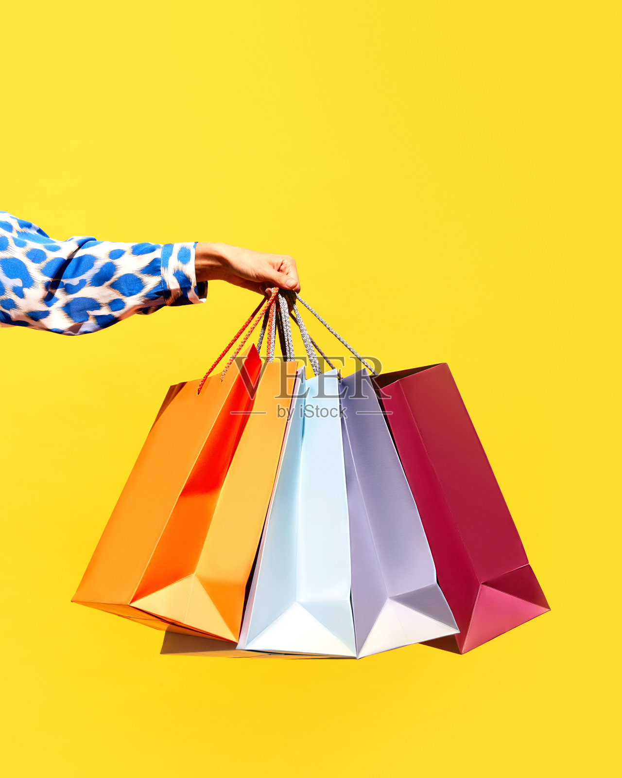 销售报价。“黑色星期五”。购物折扣。女士手持购物袋的特写被隔离在明亮的黄色背景上。照片摄影图片