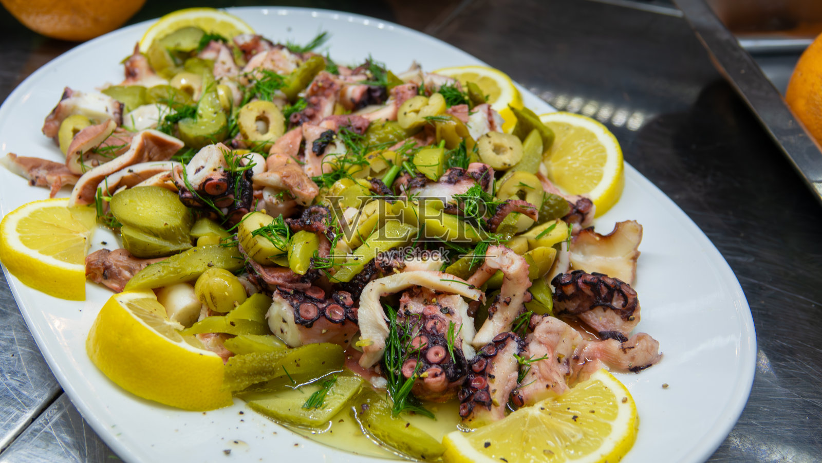 煮章鱼沙拉配上纯橄榄油、柠檬片、莳萝、绿橄榄和腌黄瓜照片摄影图片