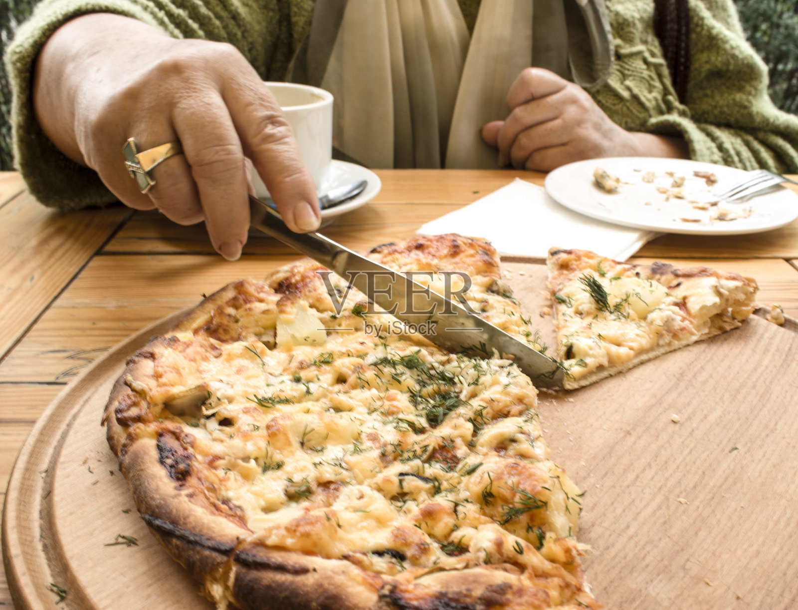 手拿刀切披萨。照片摄影图片