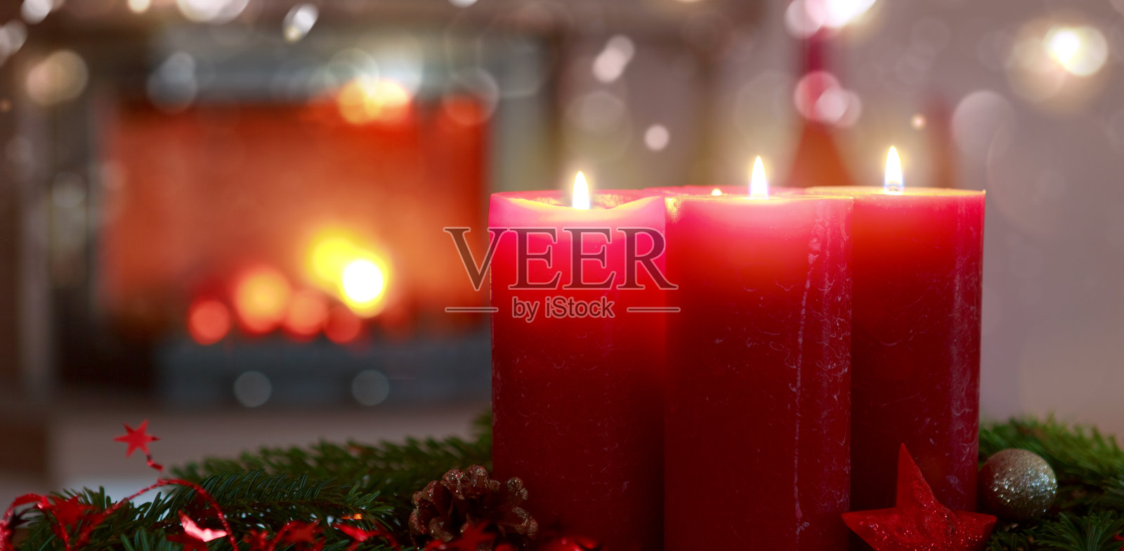 四个燃烧的红色降临节蜡烛在一个温暖的内部壁炉。照片摄影图片