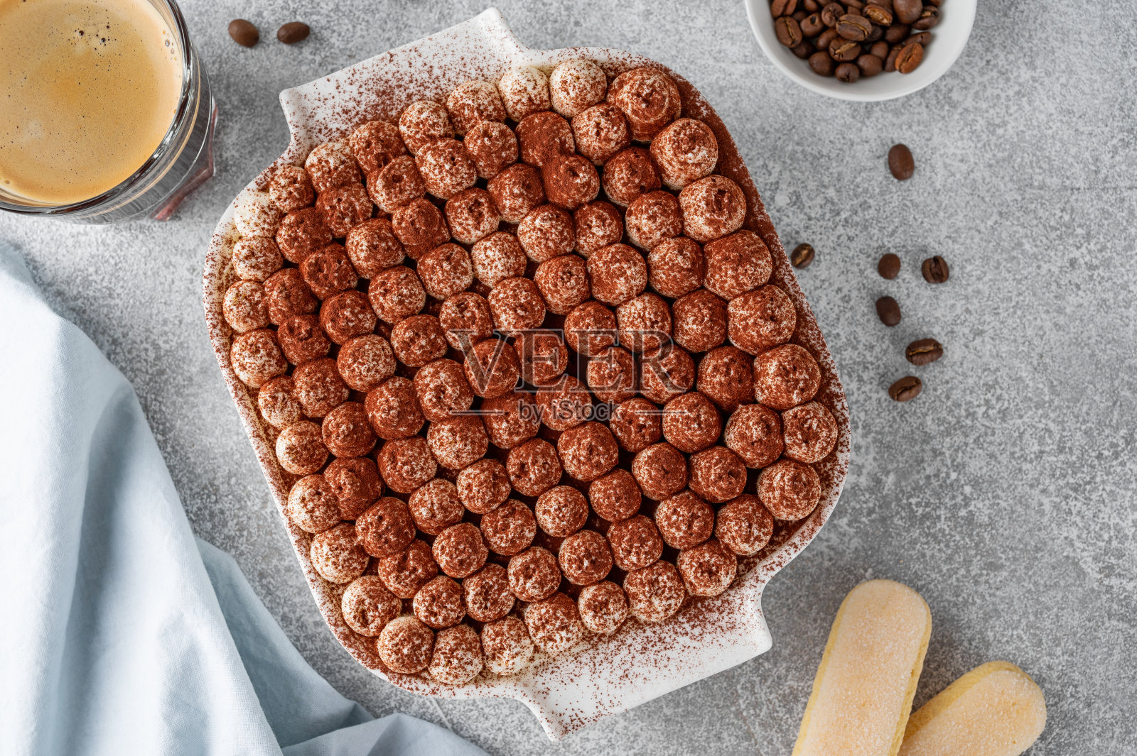 传统的意大利分层甜点提拉米苏与马斯卡彭奶油和饼干在白色的烤盘在灰色的混凝土背景。照片摄影图片