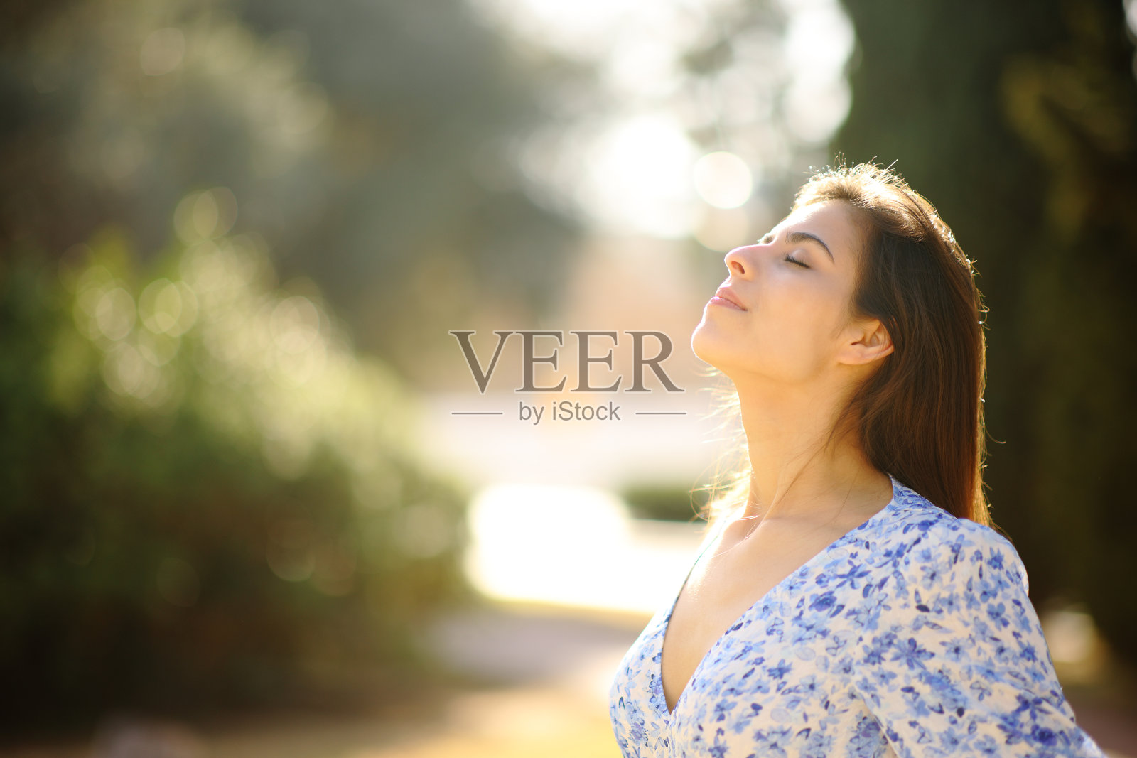 在阳光明媚的公园里呼吸新鲜空气的快乐女人照片摄影图片