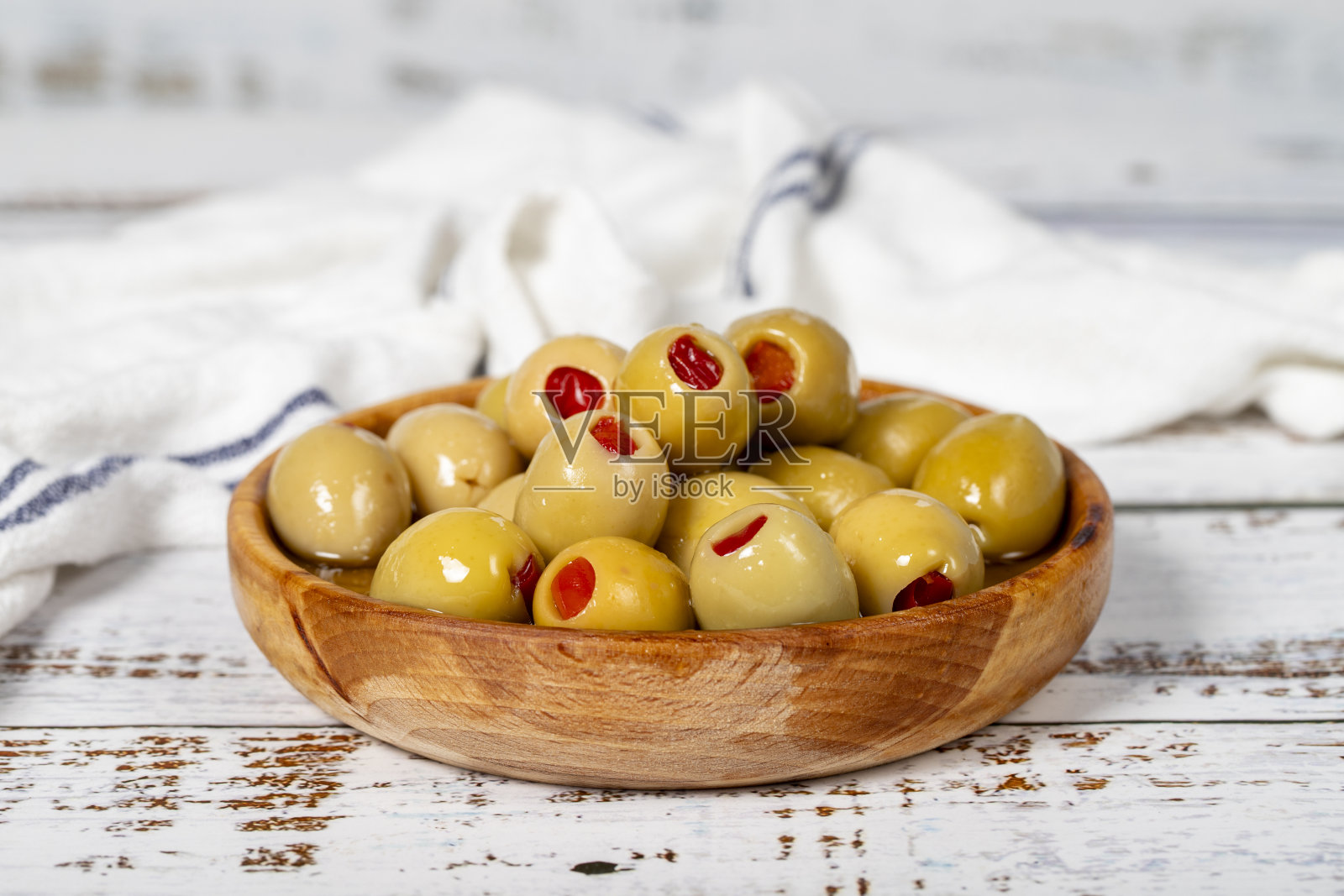 木碗里的青椒橄榄。白色木材背景上的橄榄。地中海食物。素食照片摄影图片