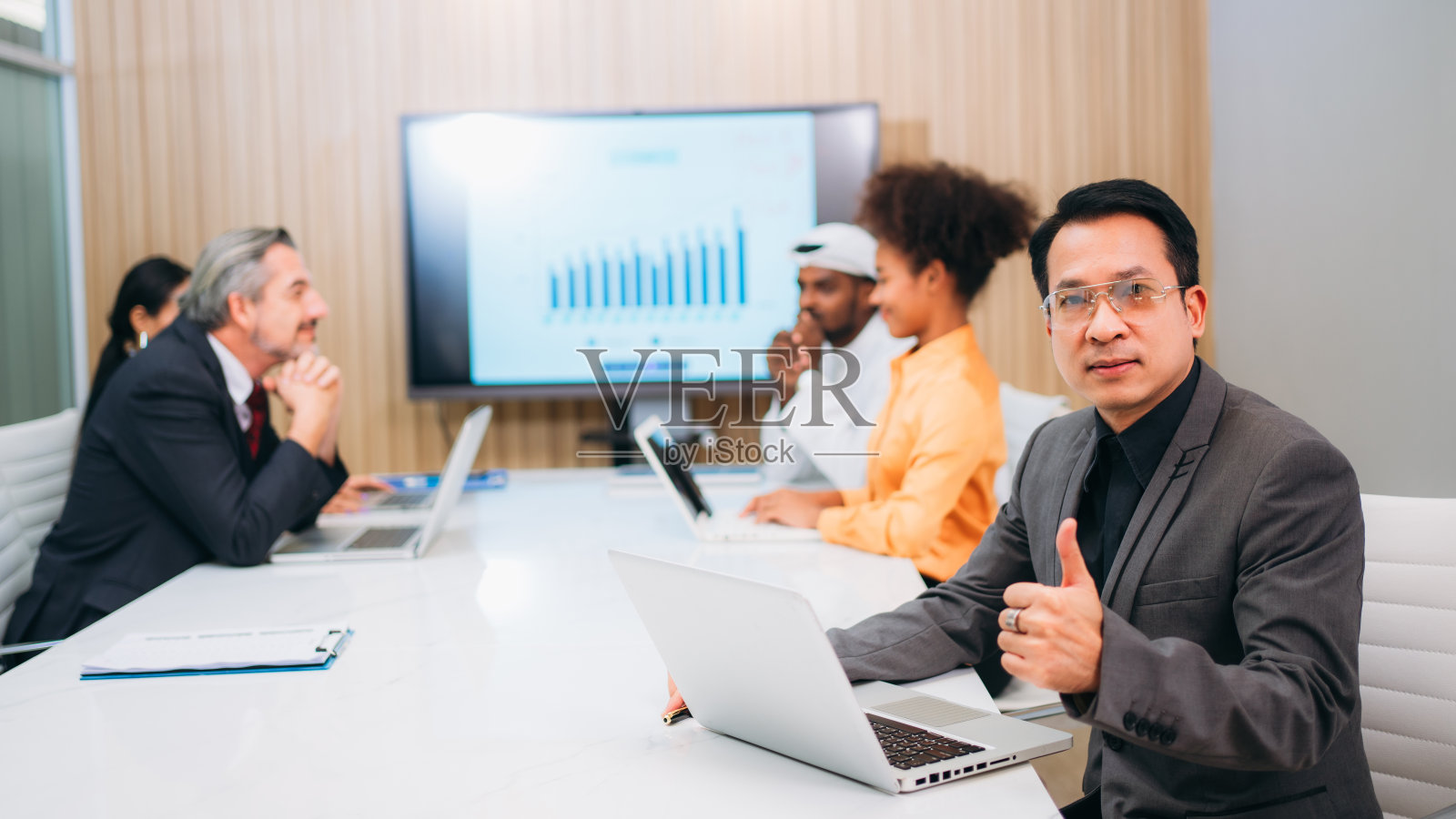 商业领袖的肖像，看着相机，在工作空间竖起大拇指。现代办公室中多元化的年轻专业人士:协作与创新。照片摄影图片