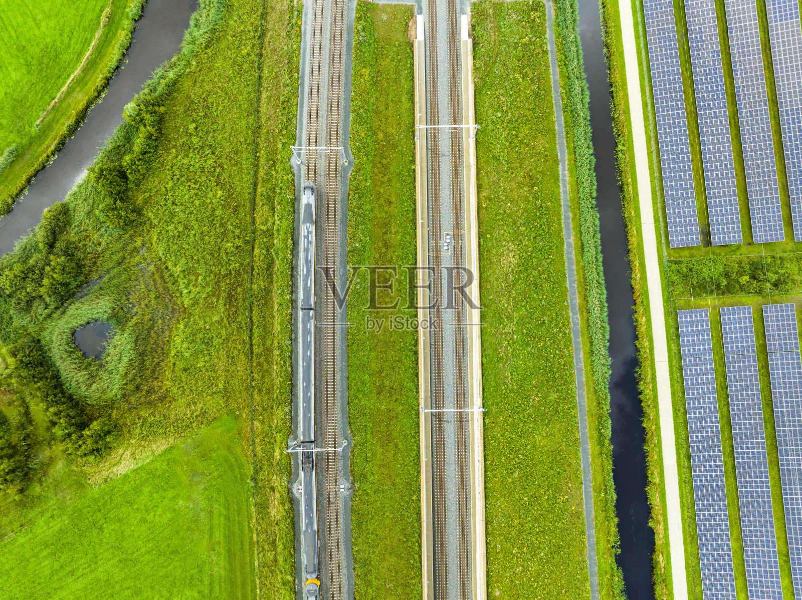 从上面看，铁轨上有一列火车经过，旁边是一片太阳能电池板照片摄影图片