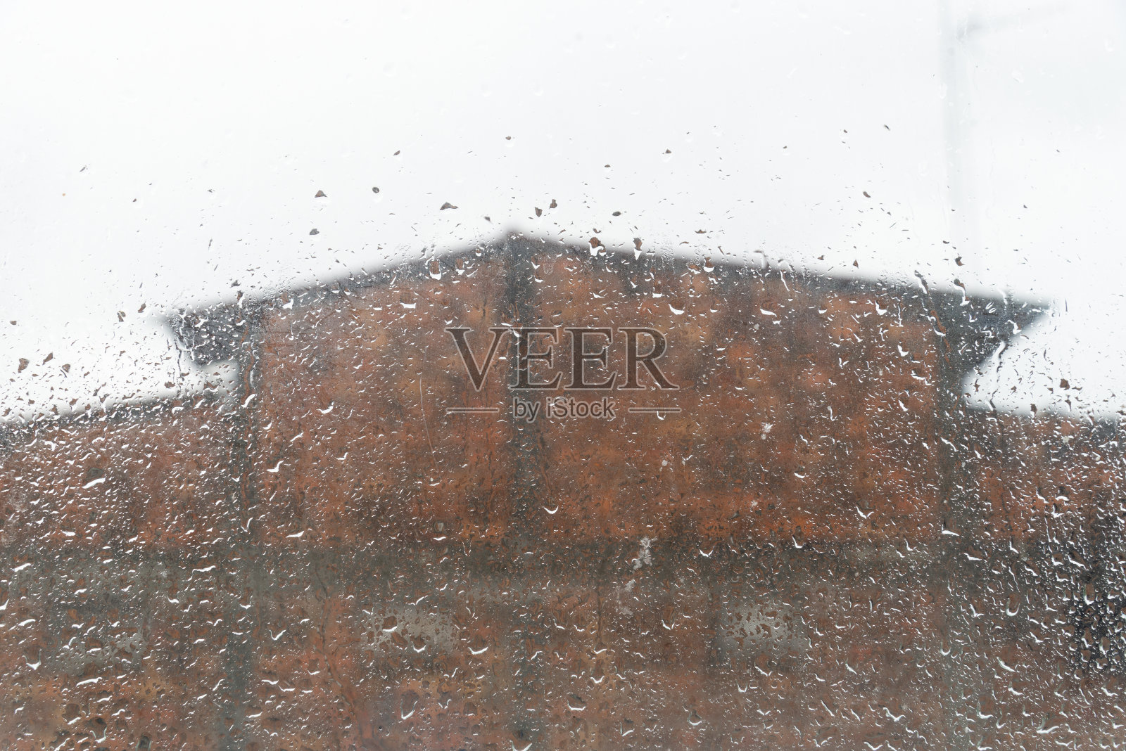 透过沾有雨点的湿玻璃，可以看到正在建造的房屋的正面。照片摄影图片