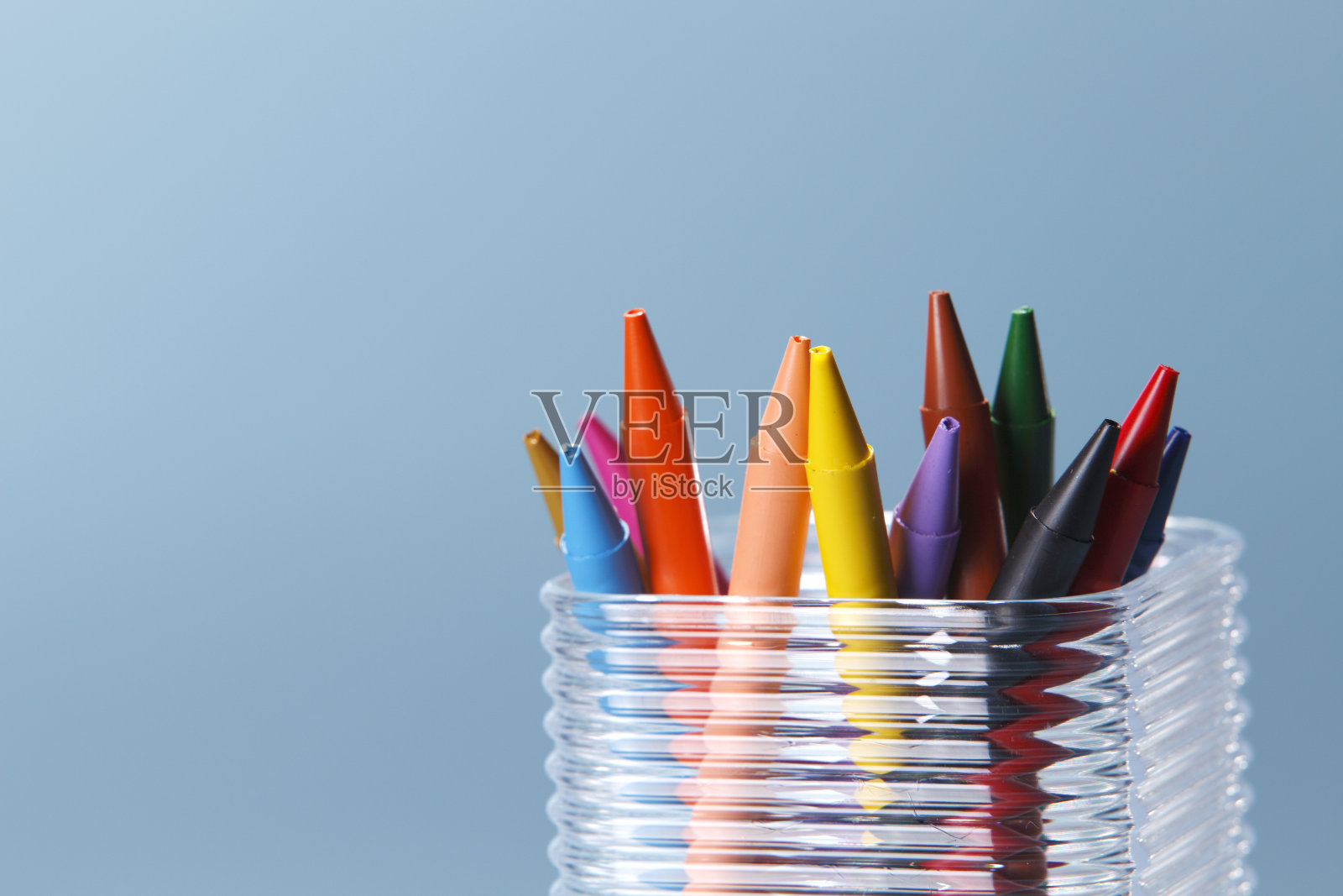 透明的丙烯酸盒子里装满了蜡笔。照片摄影图片