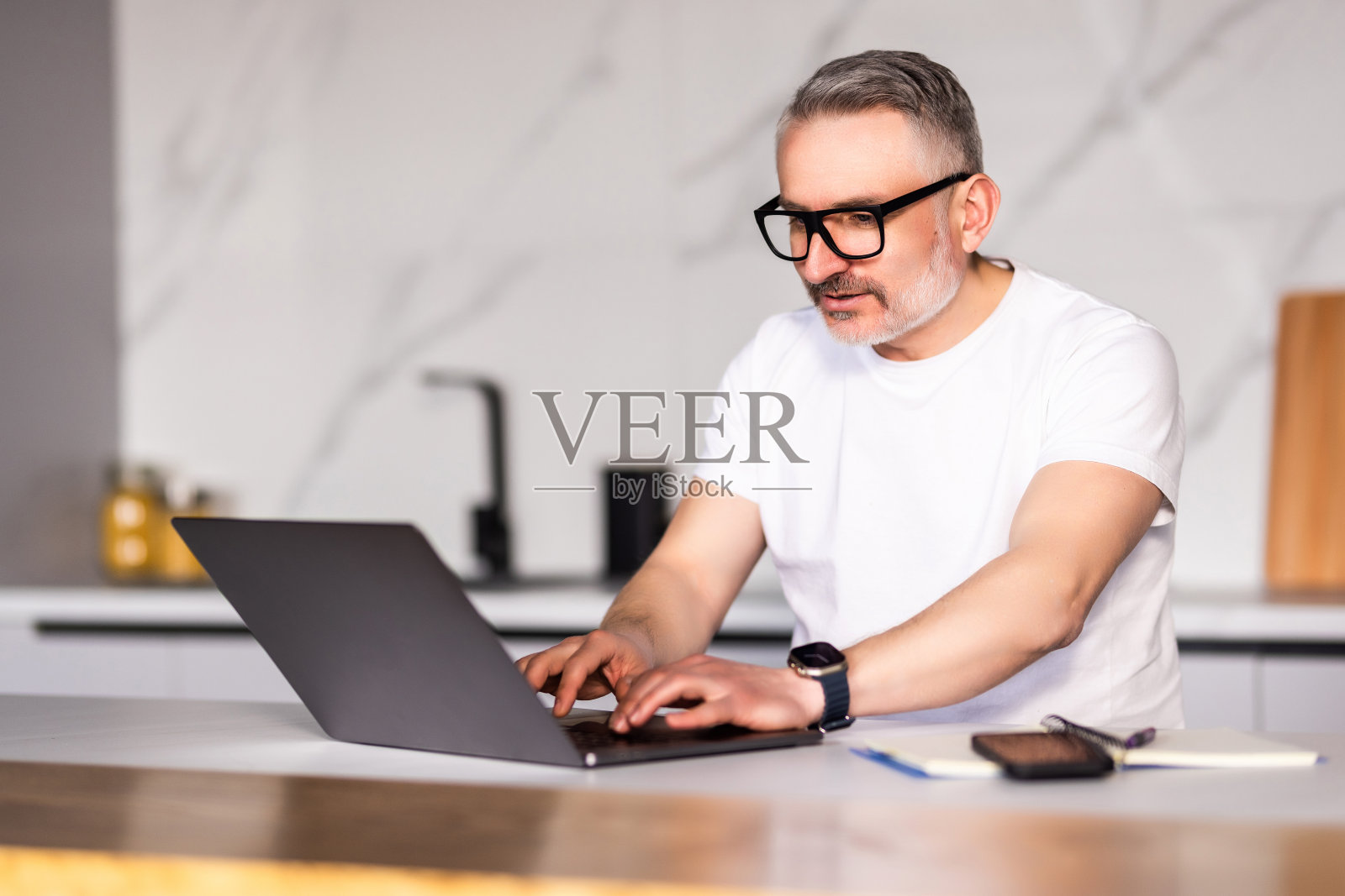 帅哥在厨房用笔记本电脑。在家办公照片摄影图片