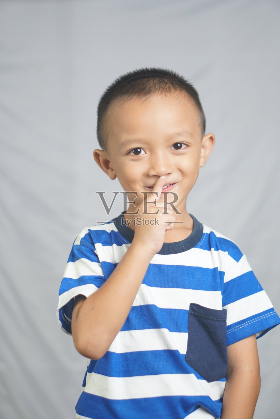 男孩把手指伸进鼻子里。照片摄影图片