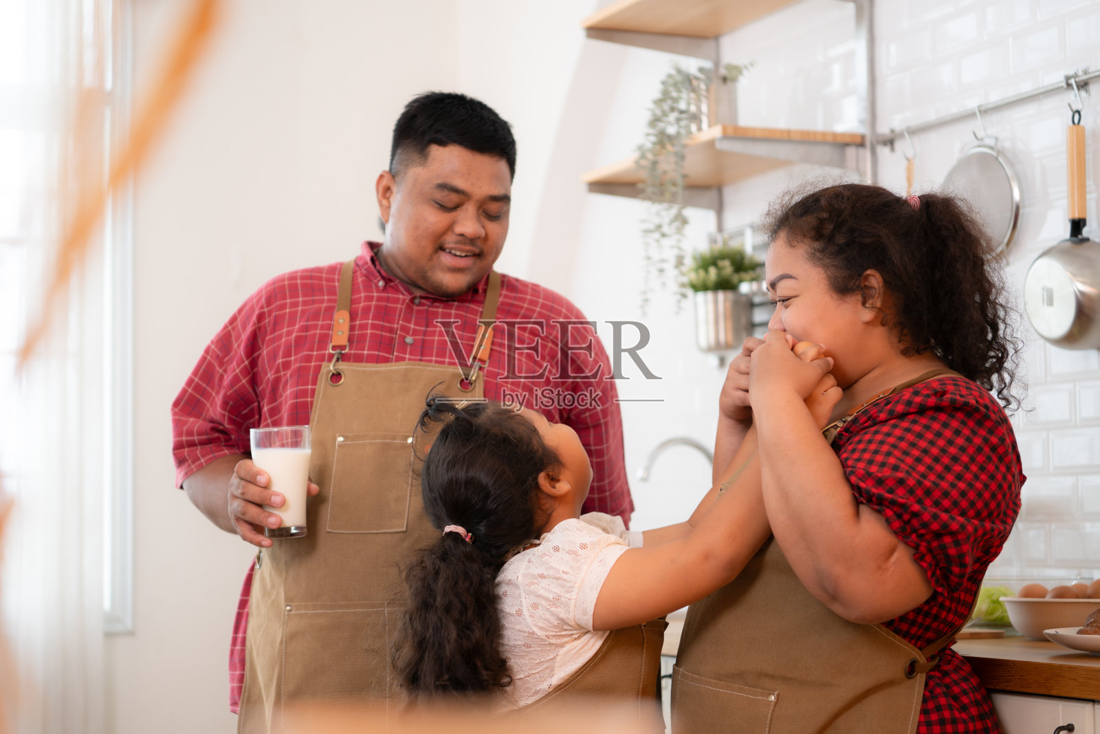 一个大码的家庭，父亲戴着假腿，做饭后一起吃饭，女儿在家里的餐厅喝牛奶照片摄影图片