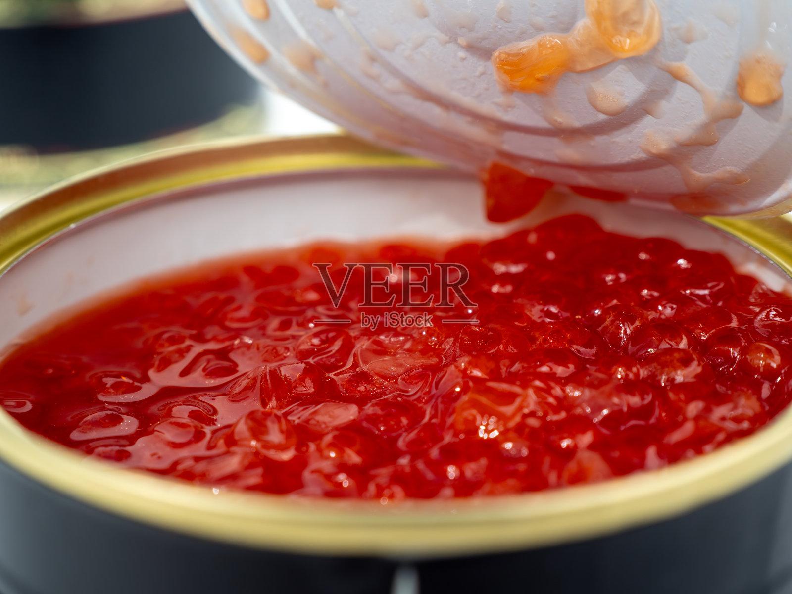 打开白底红鱼子酱罐头。照片摄影图片