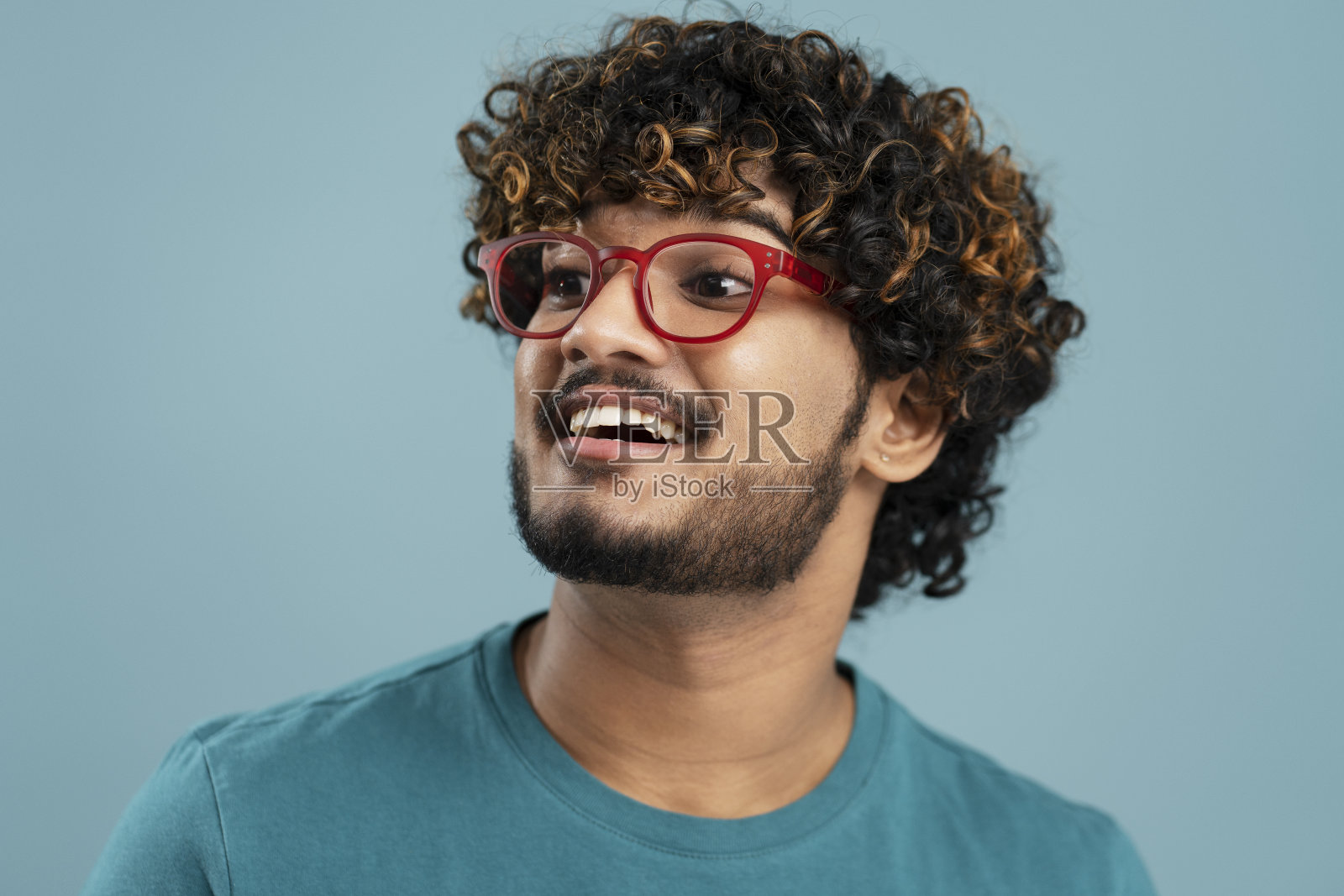 一个微笑自信的印度男人，戴着一副时髦的红色眼镜，看着远处的背景照片摄影图片