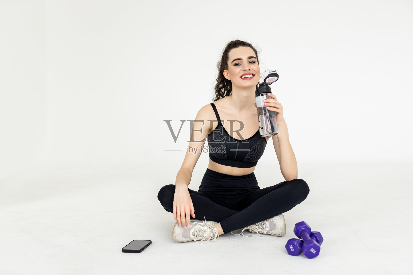 年轻女子在家里健身后拿着一瓶水照片摄影图片