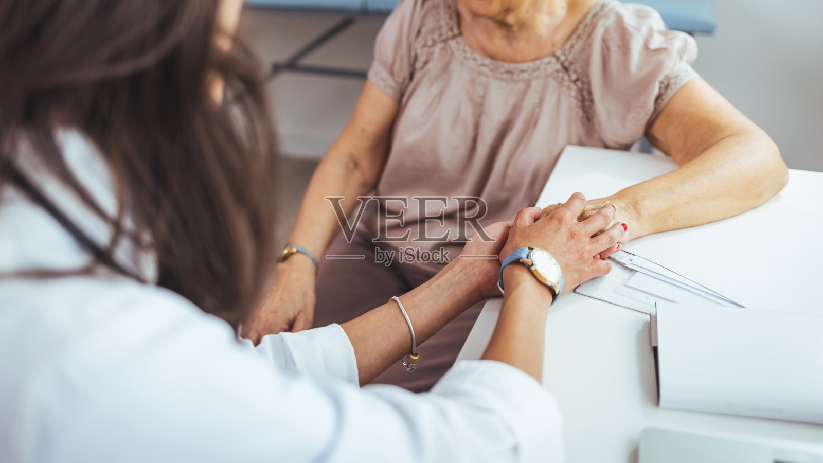 一名女护士握着她的老年病人的手。照片摄影图片